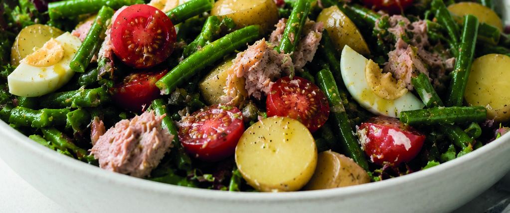 A platter of Niçoise salad with green beans, cherry tomatoes, baby potatoes, boiled eggs and tuna.