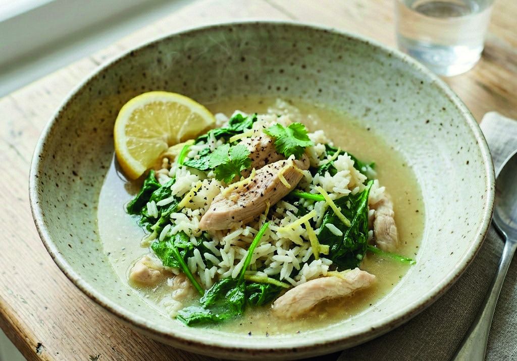 A bowl of rice, chicken and wilted spinach in a gingery broth with lemon.